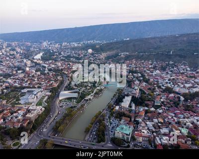 Drohnenansicht der Altstadt in der Nähe von Hügeln und Fluss am Sommertag in Tiflis, Georgien Stockfoto