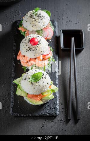 Gesunder und schmackhafter Sushi-Burger mit Gemüse und Meeresfrüchten als japanische Vorspeisen. Sushi mit Meeresfrüchten, die auf einzigartige Weise zubereitet werden. Stockfoto