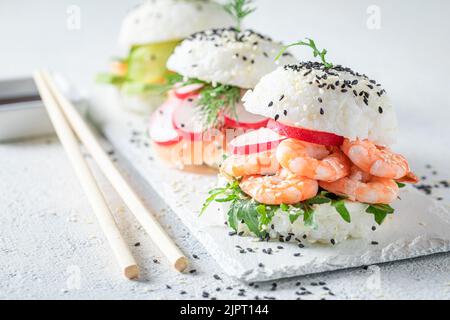 Einzigartiger und köstlicher Sushi-Burger mit Avocado und Lachs auf dem strone-Teller. Japanisches Dessert aus Meeresfrüchten und Reis. Stockfoto