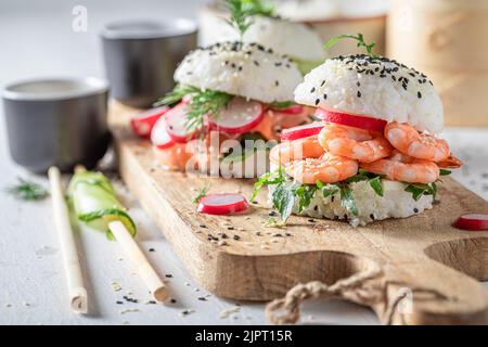 Einzigartiger und köstlicher Sushi-Burger mit Meeresfrüchten und Reis als japanische Vorspeisen. Sushi mit Meeresfrüchten, die auf einzigartige Weise zubereitet werden. Stockfoto