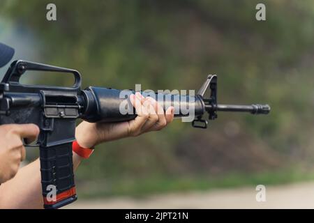 Hände zielen auf Maschinengewehr. Schusswaffenausbildung. Zielgerichtete Übung im Schießbereich. Unscharfer Hintergrund horizontal. Hochwertige Fotos Stockfoto