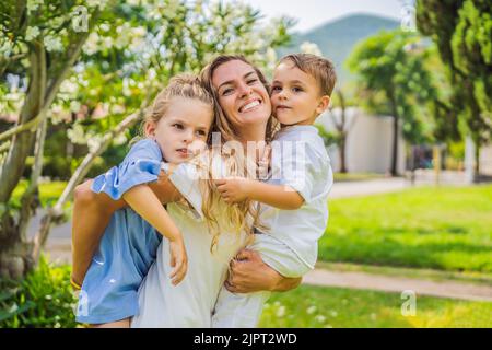 Glückliche Familie im Freien auf dem Gras in einem Park, lächelnde Gesichter, Spaß habend Porträt eines verärgerten Mädchens, das an einem Kaffeetisch sitzt Stockfoto