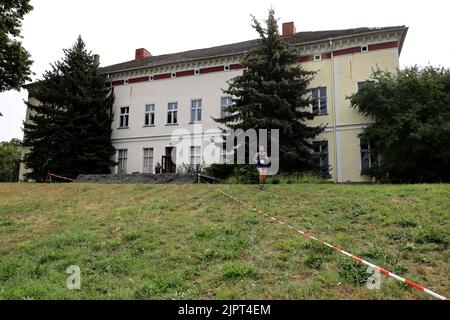 Genthin, Deutschland. 20. August 2022. Teilnehmer der '6. Genthiner Matsch-Wolke' laufen vom Schloss Parchen aus durch. 270 Teilnehmer kämpfen sich durch Staub, Schlamm, Kletterwände und über zwanzig weitere Hindernisse. In diesem Jahr führt der 12 Kilometer lange Hindernisparcours auch durch das Herrenhaus Parchen. Quelle: Peter Gercke/dpa-Zentralbild/dpa/Alamy Live News Stockfoto