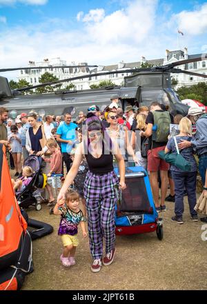 Eastbourne, East Sussex, Großbritannien, 20. September 2022. Eine Mutter mit ihrer kleinen Tochter geht an einer Schlange von Menschen vorbei, die Schlange stehen, um einen RAF Chinook-Hubschrauber bei der jährlichen Eastbourne Airshow zu besuchen, einer der größten kostenlosen Veranstaltungen dieser Art im Land. Viele Flugzeuge werden fliegen, darunter Spitfires, das Red Arrows Display Team, der Battle of Britain Memorial Flight und viele andere. Quelle: Andy Soloman/Alamy Live News Stockfoto