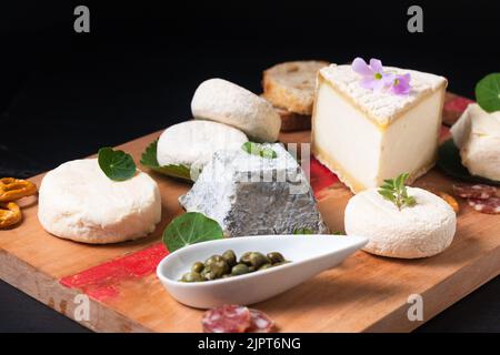 Food Concept Sortiment französischer Bio-Frischkäse aus Ziege auf Holzkäseplatte auf schwarzem Hintergrund mit Kopierfläche Stockfoto