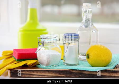 Natürliche Bio umweltfreundliche Hausreinigungsgeräte Zutaten, Essig, Zitrone, Backpulver, Zitronensäure auf Holzblech auf Fensterbank, Fenster. Stockfoto
