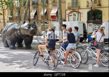 BARCELONA, SPANIEN - 18. JUNI 2022: Gruppe von Fahrradtouristen, die die Katze von Fernando Botero in Barcelonas Rabal rambla betrachten. Stockfoto