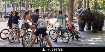 BARCELONA, SPANIEN - 15. JUNI 2022: Gruppe von Fahrradtouristen, die die Katze von Fernando Botero in Barcelonas Rabal rambla betrachten. Stockfoto