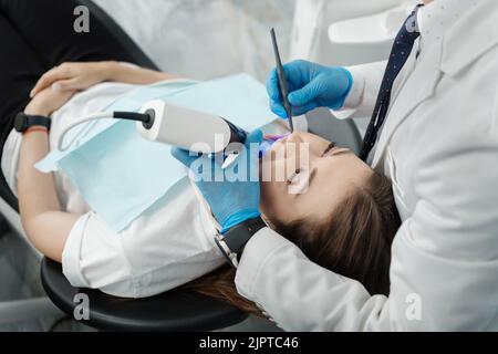 Nahaufnahme einer Patientin im Zahnarztstuhl bei einem Verfahren der intraoralen digitalen Untersuchung ihrer Zähne. Moderner 3D Dental-Scanner Stockfoto