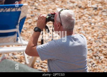 Eastbourne, East Sussex, Großbritannien, 20. September 2022. Ein Mann schaut durch ein Fernglas, während er eine Ausstellung auf der jährlichen Eastbourne Airshow, einer der größten kostenlosen Veranstaltungen dieser Art im Land, sieht. Viele Flugzeuge flogen, darunter Spitfires, das Red Arrows Display Team, der Battle of Britain Memorial Flight und viele andere. Stockfoto