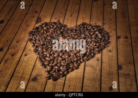 Die Herzform aus Kaffeebohnen auf Holzoberfläche. Stockfoto