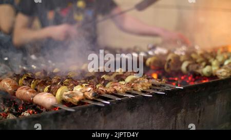 Gegrillter Kebab auf Metallspieß in Nahaufnahme. Gebratenes Fleisch, gekocht am Grill. BBQ frisches Rindfleisch Fleisch hacken Scheiben. Traditionelles östliches Gericht, Shish Kebab. Grill auf Holzkohle und Flamme, Picknick, Street Food. Hochwertige Fotos Stockfoto