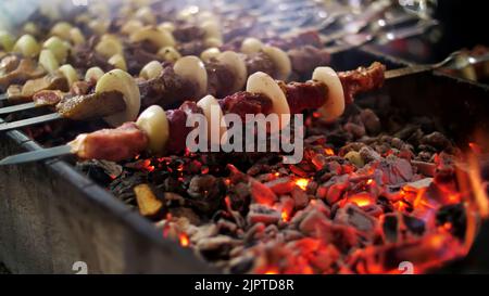 Den Schischebab aus dem Schweinefleisch, auf den Spiessen, braten auf den roten heißen Kohlen. Hochwertige Fotos Stockfoto