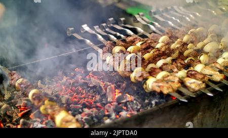 Gegrillter Kebab beim Kochen auf Metallspieß aus nächster Nähe. Gebratenes Fleisch, gekocht am Grill. Grill auf Holzkohle und Flamme, Picknick, Street Food. Hochwertige Fotos Stockfoto