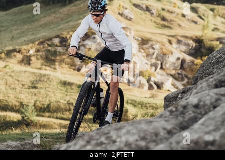 Nahaufnahme professioneller Radsportler mit Mountainbike auf dem Trail im felsigen Gelände Stockfoto