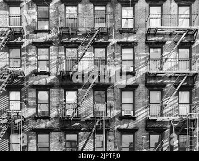 Außenansicht von alten Wohngebäuden mit Fenstern und Feuertreppen in New York City NYC in Schwarz und Weiß Stockfoto