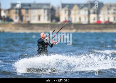 Troon, Großbritannien. 20. August 2022. Starke südwestliche Flügel lockten eine Reihe von Kitesurfern in die Bucht vor dem Strand von Troon. Die teilweise bis zu 25mph stürzenden Winde am Firth of Clyde boten ideale Bedingungen für den Sport. Kredit: Findlay/Alamy Live Nachrichten Stockfoto