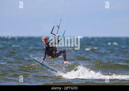 Troon, Großbritannien. 20. August 2022. Starke südwestliche Flügel lockten eine Reihe von Kitesurfern in die Bucht vor dem Strand von Troon. Die teilweise bis zu 25mph stürzenden Winde am Firth of Clyde boten ideale Bedingungen für den Sport. Kredit: Findlay/Alamy Live Nachrichten Stockfoto