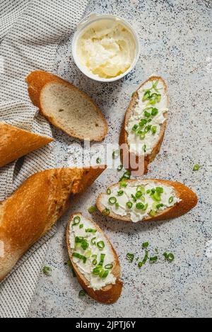 Frisches und leckeres knuspriges Baguette mit Frischkäse und Schnittlauch Stockfoto