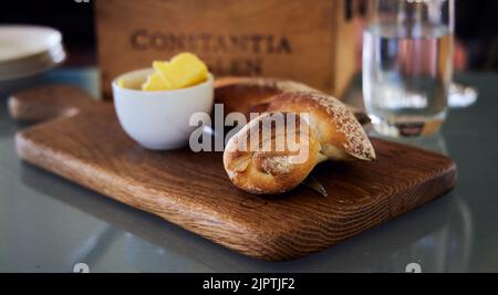 Nahaufnahme von Brot und Butter auf einem hölzernen Schneidebrett auf dem Tisch im Constantia Glen Wine Estate South Africa Stockfoto