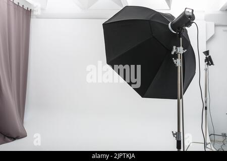 Innenraum des hellen Raums des Fotostudios mit großem weißen Zyklorama mit Beleuchtungsausrüstung Stockfoto