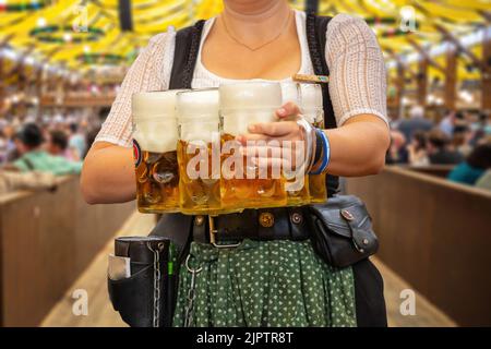 Oktoberfest, München. Kellner in traditioneller bayerischer Tracht serviert Bier, Nahaufnahme. Oktober Fest Deutsches Bierfest. Stockfoto