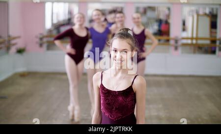 Porträt einer jungen Balletttänzerin in einem fliederndem Balletttrikot, lächelnd, anmutig eine Ballettfigur darstellend. Hochwertige Fotos Stockfoto