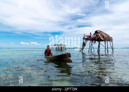 Semporna, Malaysia - 28. August 2022: Seegypsy oder bajau laut Frau, die im nahe gelegenen Stelzenhaus in Sabah Borneo Malaysia ein Boot paddelt. Stockfoto