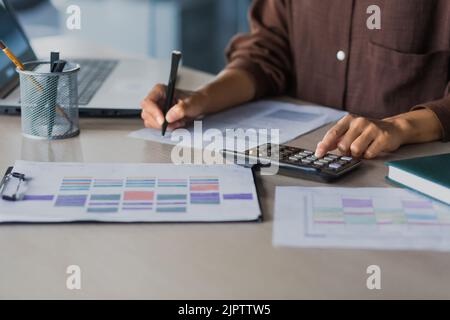 Nahaufnahme der Hand einer Geschäftsfrau bei der Arbeit, ausgewählter Fokus, berechnet eine Buchhalterin auf einem Rechner und signiert Finanzberichte und Dokumente Stockfoto