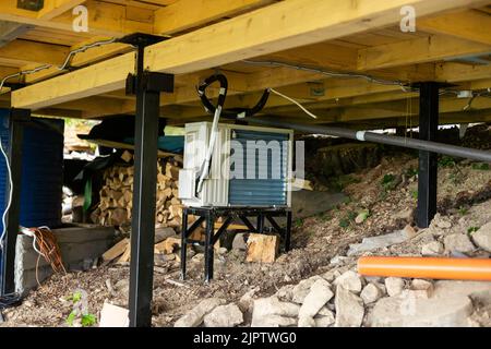 Neue moderne Klimaanlage Klimaanlage externe Kompressor-Einheit für die Installation oder den Ersatz in der Nähe der Wand von Holz-Log Wohn-Landhaus vormontiert Stockfoto