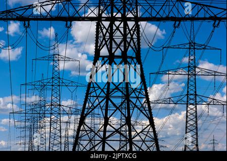 Viele elektrische Pole vor dem Himmel mit Wolken Stockfoto