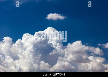 Nahaufnahme der Billowy Cumulus Wolken. Wispy Wolken, tiefblauer Himmel im Hintergrund. Stockfoto