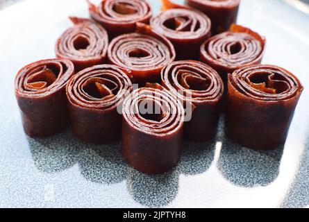 Natürliche und gesunde Snack-Lebensmittel - Fruchtpastille aus Pflaumen auf einem blauen Teller. Pastille Obstbrötchen. Fruchtmarschall. Hausgemachte Pflaumenmarmelibe. Stockfoto