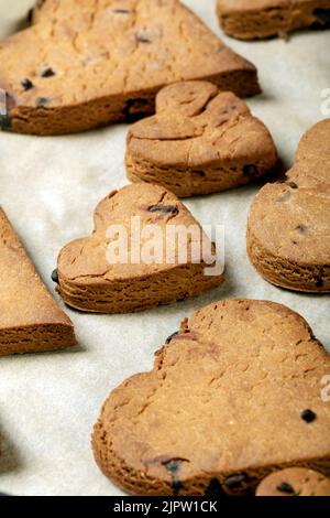 Herzförmige Kekse mit Schokoladentropfen auf einem Backblech Stockfoto
