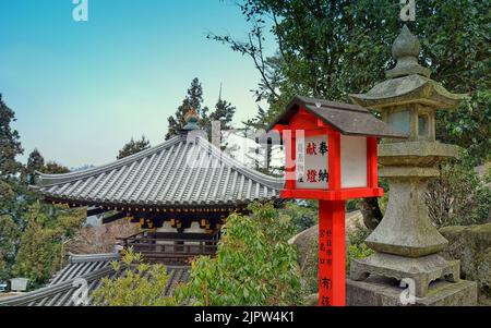 Dachdetails und traditionelle Laternen am Reikado-Schrein, Halle der ewigen Flamme. Insel Miyajima, Japan. Stockfoto