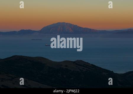 Schifffahrt in der Straße von Gibraltar in der Abenddämmerung. Spanien im Vordergrund und Marokko im Hintergrund. Der Berg ist Jebel Musa (oder Jbel Moussa) und wird gedacht Stockfoto