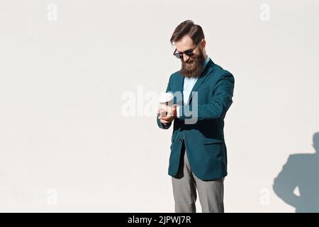 Stilvoller Mann mit Bart, der an einem sonnigen Tag eine Jacke, ein Hemd und eine Fliege trägt Stockfoto