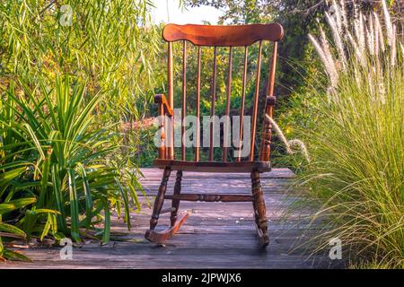 Leerer Schaukelstuhl im Garten bei Sonnenuntergang im Sommer Stockfoto