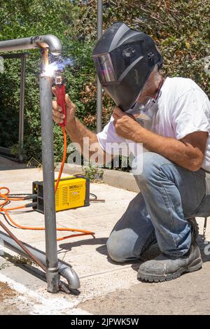 Jerusalem, Israel - 18.. Mai 2022: Ein Mann schweißen ein Metallgeländer an einem sonnigen Tag im Freien. Stockfoto