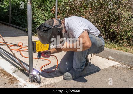 Jerusalem, Israel - 18.. Mai 2022: Ein Mann schweißen ein Metallgeländer an einem sonnigen Tag im Freien. Stockfoto