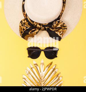 Sommer goldener Hintergrund mit Hut, Sonnenbrille und Palmblättern. Flacher, laygerer Kopierplatz Stockfoto