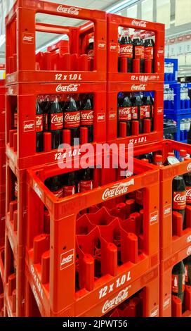 Eine vertikale Aufnahme von gestapelten roten Kisten mit Coca Cola-Flaschen in einem Supermarkt Stockfoto