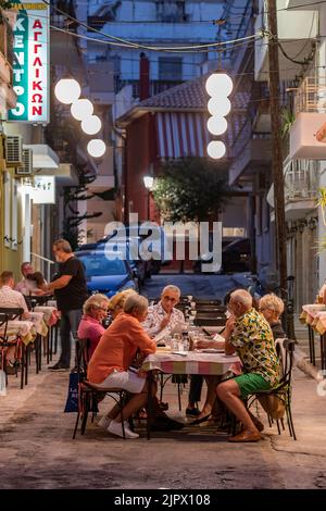 Freunde teilen sich ein Essen in einer stimmungsvollen Umgebung während des Urlaubs auf der griechischen Insel Zante oder zakynthos und essen abends in Zante. Stockfoto