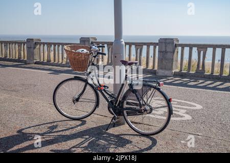 Das Damenfahrrad wurde an einem Laternenpfahl an der Strandpromenade in der Stadt Lowestoft in Suffolk verriegelt und angekettet Stockfoto