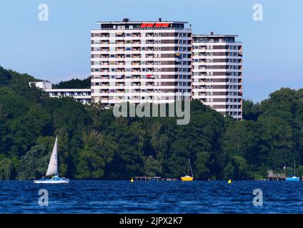 09. August 2022, Schleswig-Holstein, Plön: 09.08.2022, Ploen. In Ploen stehen zwei Hochhäuser. Vor ihnen ist der große Ploen See zu sehen, auf dem ein Seemann mit seinem Beiboot segelt. (Aufnahme mit einem starken Teleobjektiv). Foto: Wolfram Steinberg/dpa Foto: Wolfram Steinberg/dpa Stockfoto