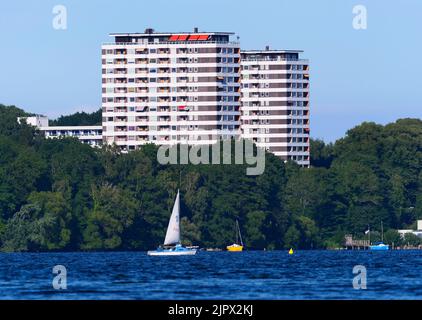 09. August 2022, Schleswig-Holstein, Plön: 09.08.2022, Ploen. In Ploen stehen zwei Hochhäuser. Vor ihnen ist der große Ploen See zu sehen, auf dem ein Seemann mit seinem Beiboot segelt. (Aufnahme mit einem starken Teleobjektiv). Foto: Wolfram Steinberg/dpa Foto: Wolfram Steinberg/dpa Stockfoto