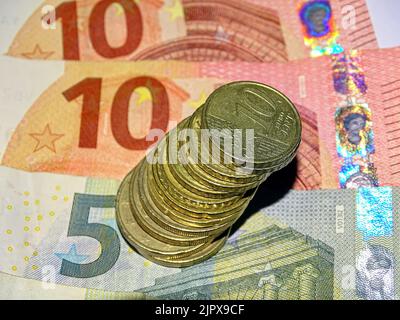 Euro-Banknoten und -Münzen aus der Nähe übereinander gestapelte Banknoten, Zehner, Fünfer und Münzen in der Draufsicht und Nahaufnahme. Stockfoto