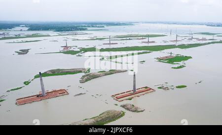 Dhaka, Bangladesch. 19. August 2022. Luftaufnahme eines Schornsteins von der lokalen Ziegelfabrik, die von Monsunregen in der Nähe von Savar, Dhaka, Bangladesch überflutet wurde. Hunderte von Ziegelfabriken scheinen nach schweren Überschwemmungen fast unter Wasser verschwunden zu sein. Die Gebäude waren während der gesamten Monsunsaison mit Wasser bedeckt, da starke Regenfälle durch einen nahe gelegenen Fluss die Ufer durchbrochen hatten.Arbeiter konnten Tausende von Ziegelsteinen retten - aber viele gingen durch das 20 Meter tiefe Hochwasser verloren. In der jüngsten Agenda der Vereinten Nationen für die Generalversammlung geht es um den „Klimawandel“. Jetzt ist es höchste Zeit, wir freuen uns auf den mont Stockfoto