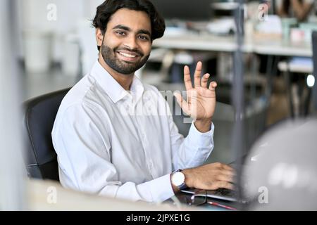 Glücklicher indischer junger Mann, Mitarbeiter des Unternehmens, der am Laptop arbeitet. Hochformat Stockfoto