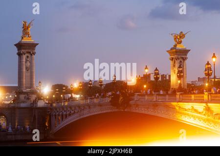 Brücke Pont Alexandre III und beleuchtete Laternenpfosten bei Sonnenuntergang. 7. Arrondissement, Paris, Frankreich Stockfoto